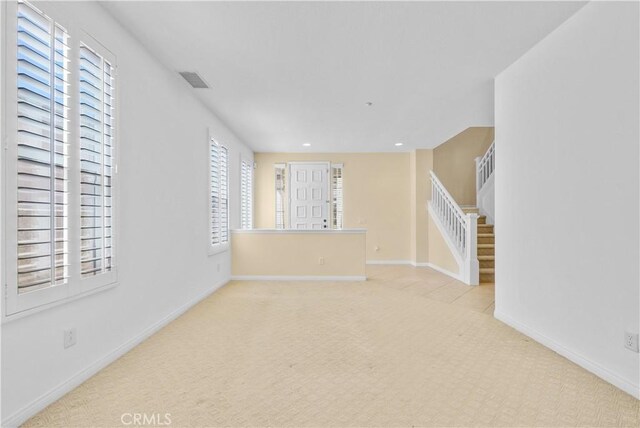 unfurnished living room featuring carpet floors and baseboards