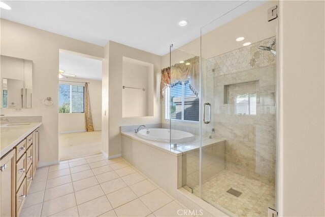 bathroom with a bath, tile patterned flooring, a shower stall, vanity, and baseboards