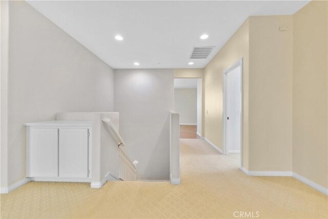 corridor with light colored carpet, baseboards, visible vents, and an upstairs landing