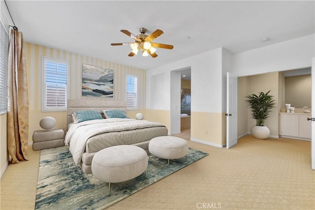 carpeted bedroom featuring connected bathroom, a ceiling fan, and baseboards