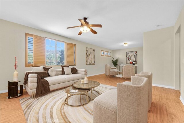 living area with ceiling fan, a healthy amount of sunlight, and baseboards