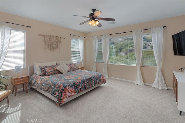 bedroom featuring baseboards, visible vents, light carpet, and ceiling fan
