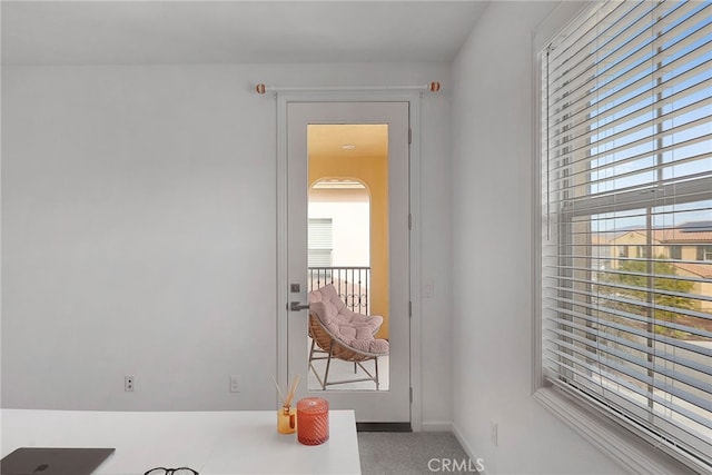 doorway with baseboards, a healthy amount of sunlight, and carpet floors