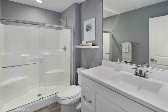 full bath with toilet, a shower stall, wood finished floors, and vanity