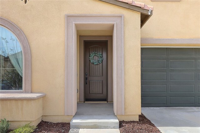 entrance to property with stucco siding and a garage