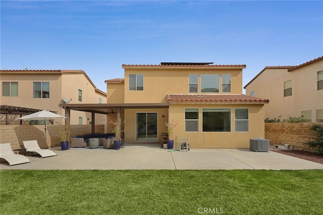 rear view of property with a patio, central air condition unit, a lawn, solar panels, and stucco siding