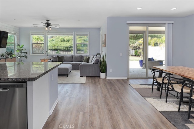 living room featuring baseboards, a ceiling fan, wood finished floors, and a healthy amount of sunlight