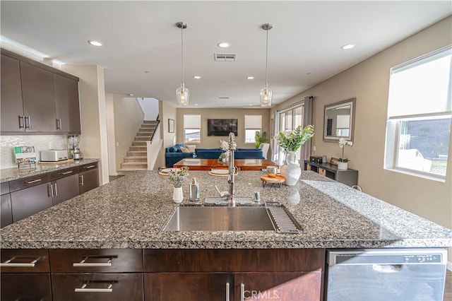 kitchen featuring dark brown cabinetry, dishwasher, a sink, and an island with sink