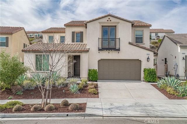 mediterranean / spanish-style house featuring concrete driveway, a balcony, a tile roof, stucco siding, and a garage