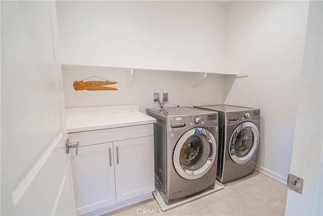 clothes washing area with separate washer and dryer, cabinet space, and baseboards