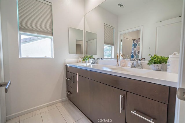 bathroom featuring baseboards, visible vents, double vanity, and a sink