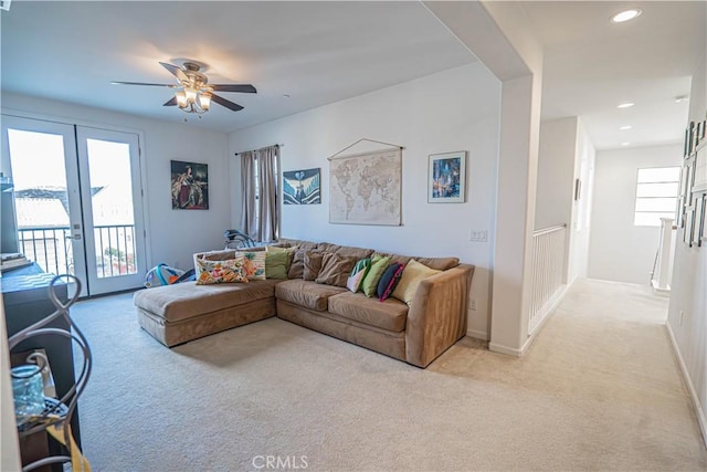 living room featuring light colored carpet, a healthy amount of sunlight, and ceiling fan