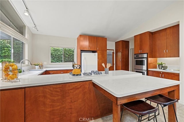 527 Bradford St, Pasadena, CA 91105 - kitchen with brown cabinetry, a peninsula, white appliances, light countertops, and a sink