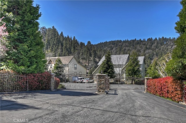 view of street featuring a gate, a gated entry, and a forest view