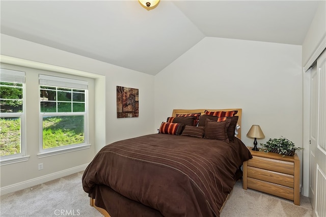 bedroom with vaulted ceiling, light colored carpet, and baseboards