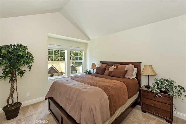 bedroom with light colored carpet, vaulted ceiling, and baseboards