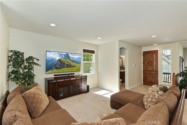 living room featuring recessed lighting, arched walkways, light colored carpet, and baseboards