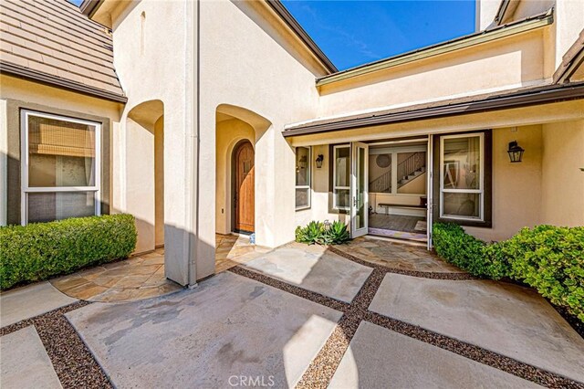 entrance to property with stucco siding and a patio area