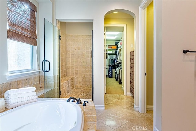 bathroom featuring a shower stall, baseboards, a bath, tile patterned floors, and a spacious closet