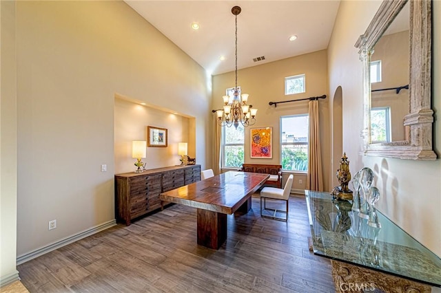 dining room featuring a chandelier, dark wood-type flooring, visible vents, baseboards, and a towering ceiling