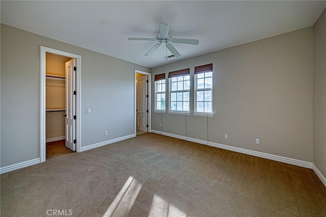 unfurnished bedroom featuring a walk in closet, carpet floors, and baseboards