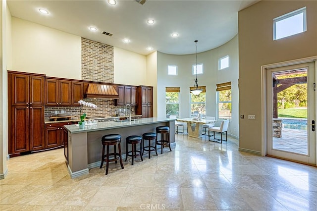 kitchen featuring a breakfast bar, a high ceiling, a sink, and a healthy amount of sunlight