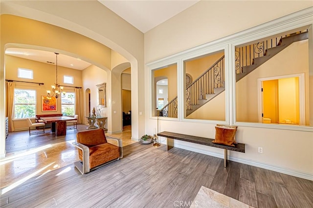 interior space with stairs, an inviting chandelier, wood finished floors, and arched walkways