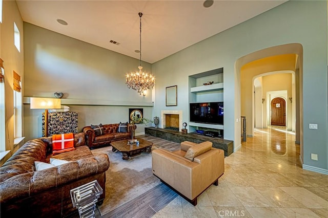 living room with a notable chandelier, built in features, visible vents, baseboards, and arched walkways