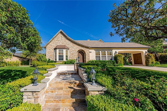 tudor home featuring stucco siding, a front lawn, and stone siding