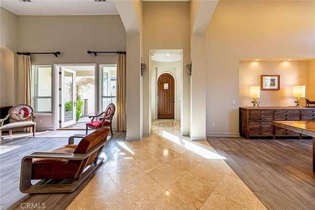 foyer with baseboards, arched walkways, and a towering ceiling