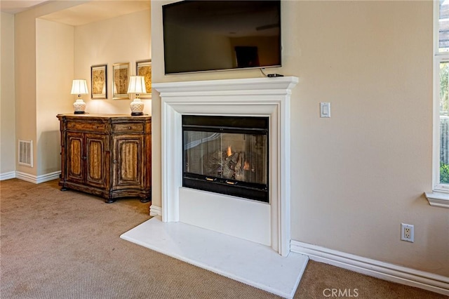 room details featuring baseboards, visible vents, carpet flooring, and a glass covered fireplace