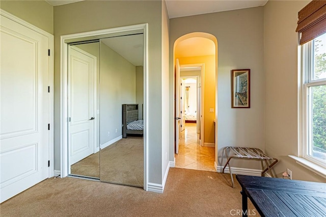 hall featuring baseboards, arched walkways, and carpet