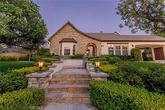 view of front of home featuring stucco siding, a tile roof, and stone siding