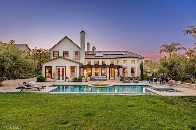 back of house with a yard, an outdoor hangout area, an in ground hot tub, french doors, and an outdoor pool