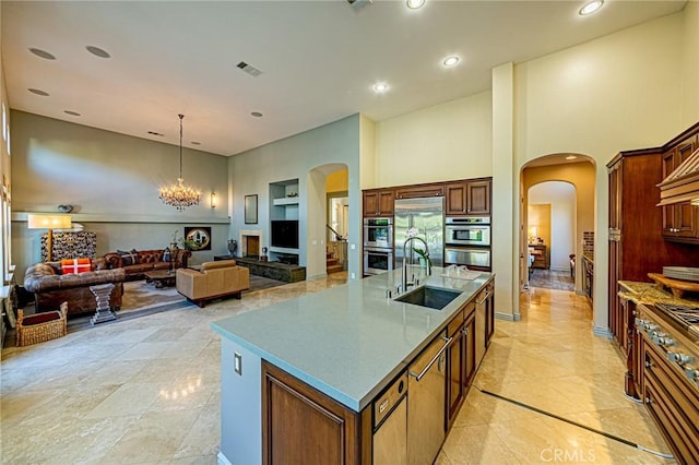 kitchen with a sink, stainless steel appliances, visible vents, a towering ceiling, and arched walkways