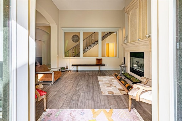 interior space featuring stairway, wood finished floors, a large fireplace, and arched walkways
