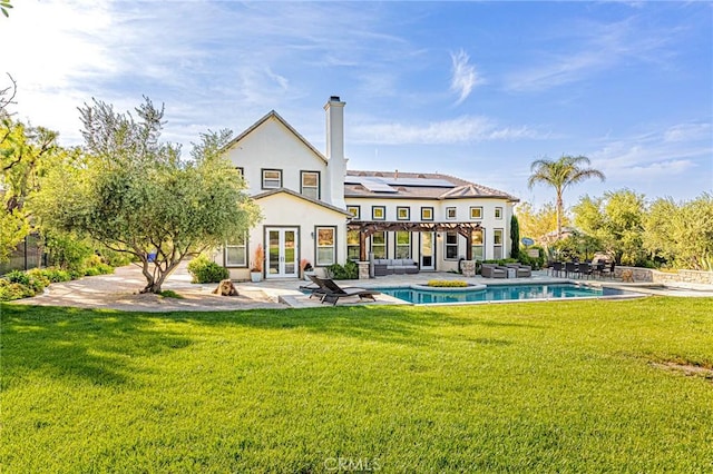 rear view of property with a chimney, an outdoor pool, a patio area, a yard, and french doors