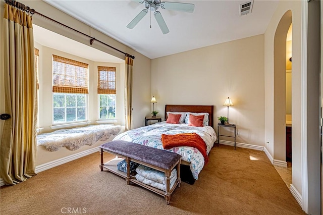 bedroom with arched walkways, carpet, baseboards, visible vents, and a ceiling fan