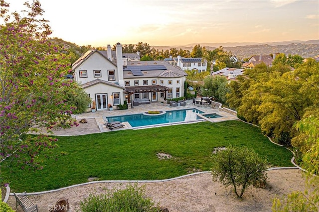 rear view of property with a patio, a yard, french doors, and a chimney