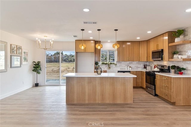 kitchen featuring light wood finished floors, open shelves, a center island, light countertops, and appliances with stainless steel finishes