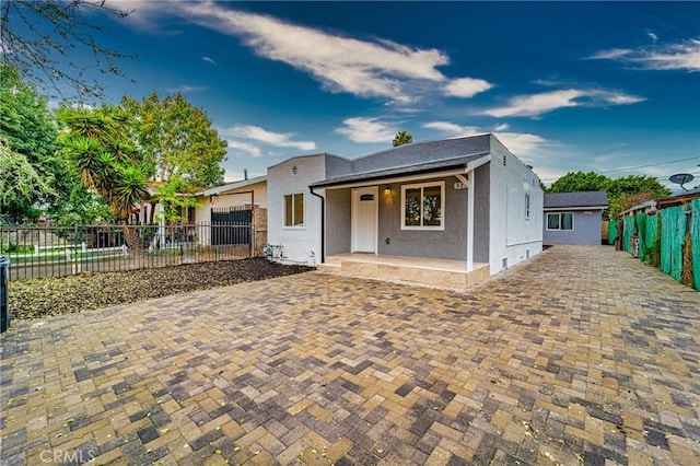 bungalow with covered porch, fence, and stucco siding
