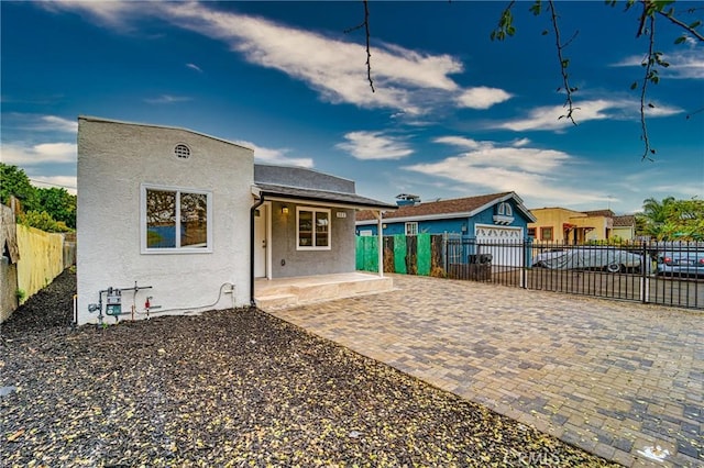 back of house featuring covered porch, fence, an outdoor structure, and stucco siding