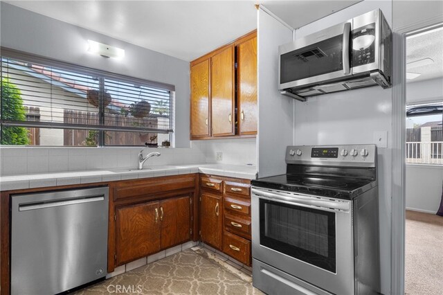 3406 Elm St, Bakersfield, CA 93301 - kitchen featuring brown cabinetry, tile countertops, appliances with stainless steel finishes, and a sink