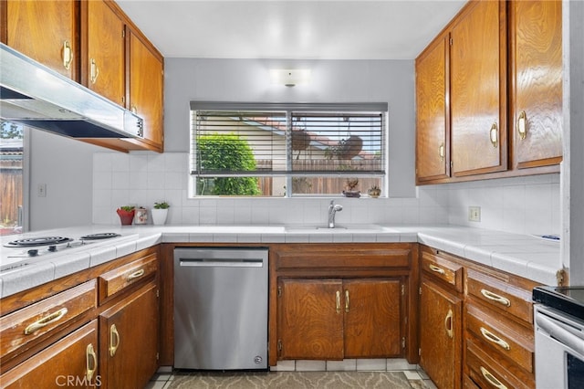 3406 Elm St, Bakersfield, CA 93301 - kitchen with brown cabinets, appliances with stainless steel finishes, under cabinet range hood, and tasteful backsplash