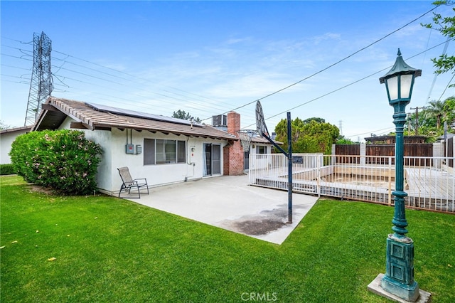 3406 Elm St, Bakersfield, CA 93301 - rear view of property featuring roof mounted solar panels, a patio area, stucco siding, a yard, and a fenced backyard