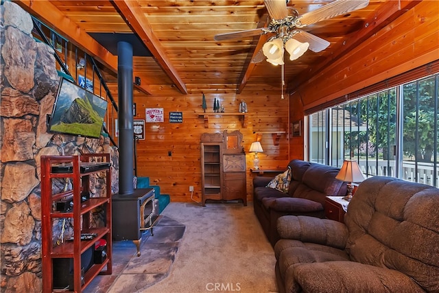 living area with wood ceiling, ceiling fan, carpet flooring, a wood stove, and wooden walls