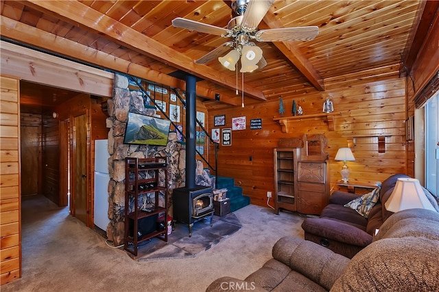 living room with wooden ceiling, beamed ceiling, carpet, wood walls, and a wood stove