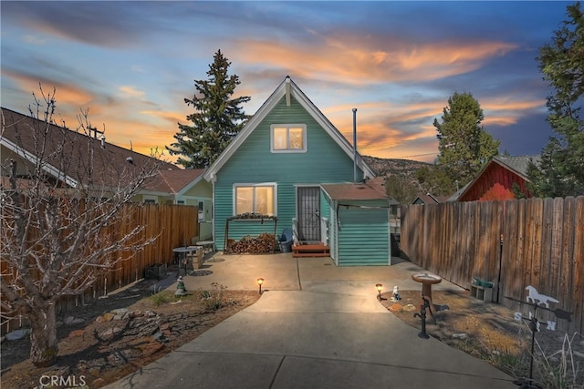 back of property at dusk with fence private yard and a patio area