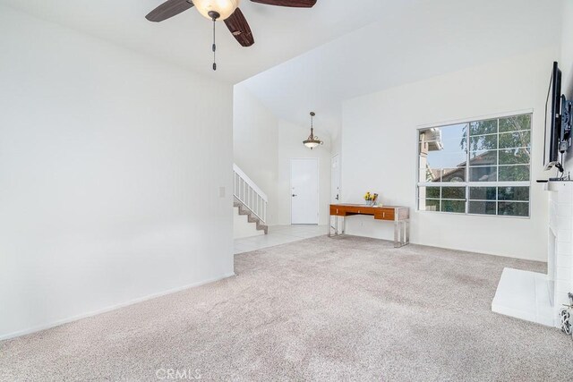 unfurnished living room with carpet, a ceiling fan, stairway, and a high ceiling