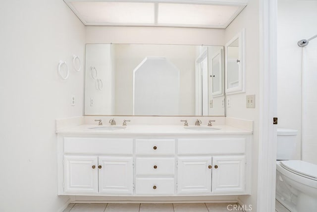 bathroom with double vanity, toilet, tile patterned flooring, and a sink